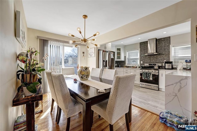 dining space with light wood-style flooring, a notable chandelier, and recessed lighting