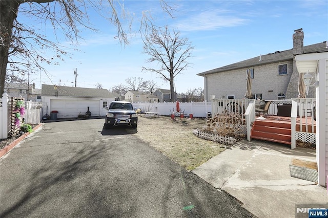 view of yard featuring a residential view, fence, a detached garage, and a wooden deck