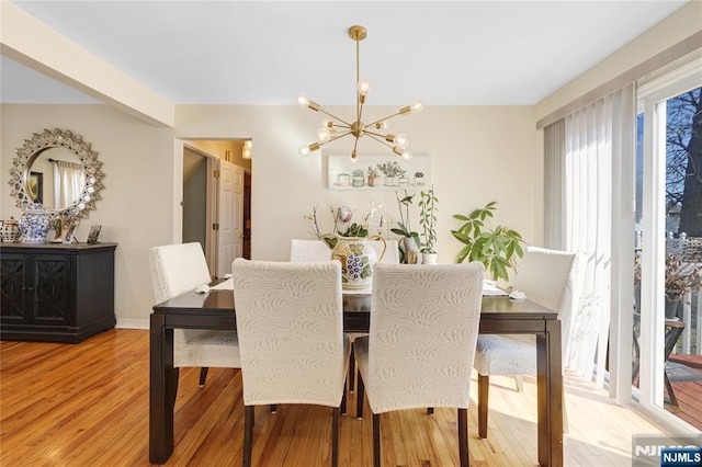 dining space with wood finished floors and an inviting chandelier