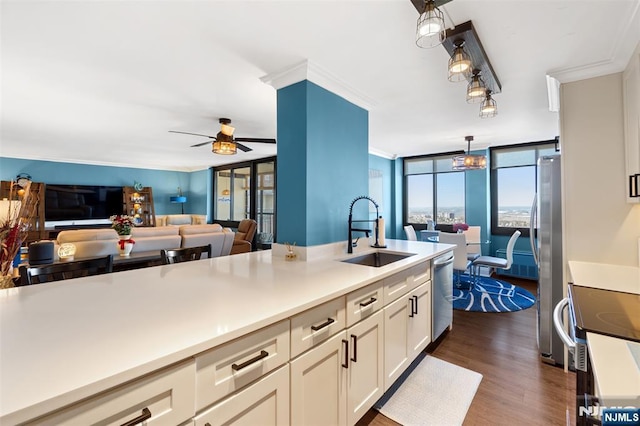 kitchen featuring open floor plan, stainless steel appliances, crown molding, light countertops, and a sink