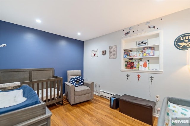 bedroom with a nursery area, light wood finished floors, baseboard heating, and recessed lighting