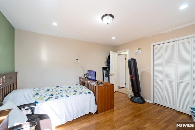 bedroom featuring a closet, baseboards, wood finished floors, and recessed lighting