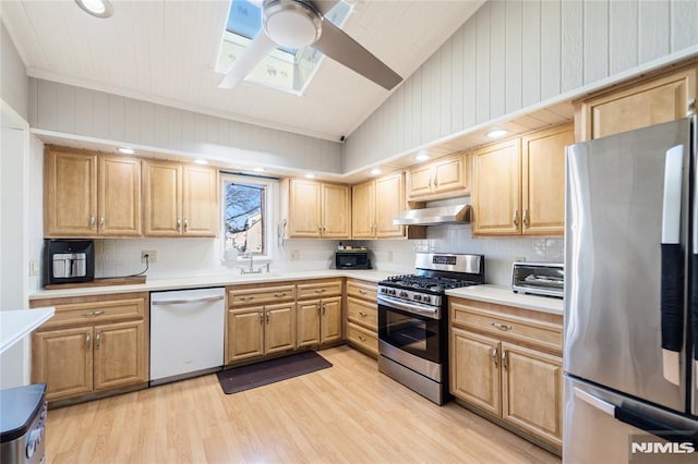 kitchen with appliances with stainless steel finishes, light wood-type flooring, light countertops, and under cabinet range hood