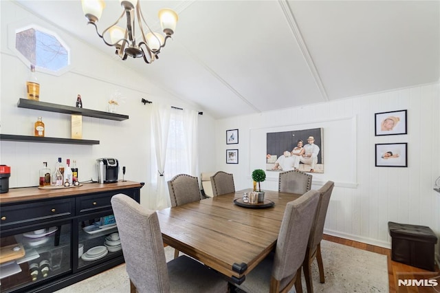 dining room with lofted ceiling, light wood finished floors, plenty of natural light, and an inviting chandelier