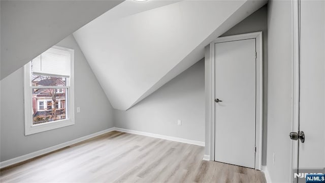 additional living space with light wood-style floors, baseboards, and vaulted ceiling