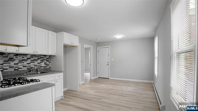 kitchen featuring decorative backsplash, white cabinets, a baseboard radiator, light wood-style floors, and a sink