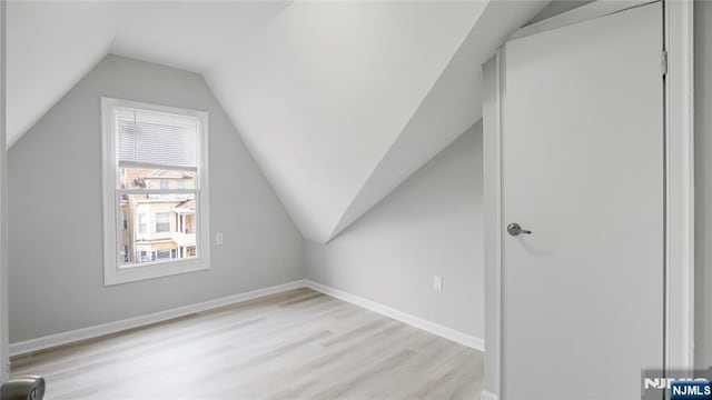 bonus room with light wood-type flooring, vaulted ceiling, and baseboards