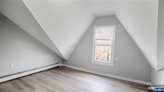 bonus room with vaulted ceiling, a baseboard radiator, baseboards, and light wood-style floors