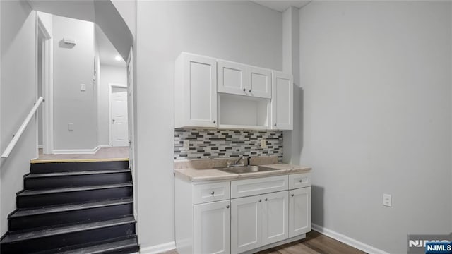 interior space featuring arched walkways, backsplash, a sink, and baseboards