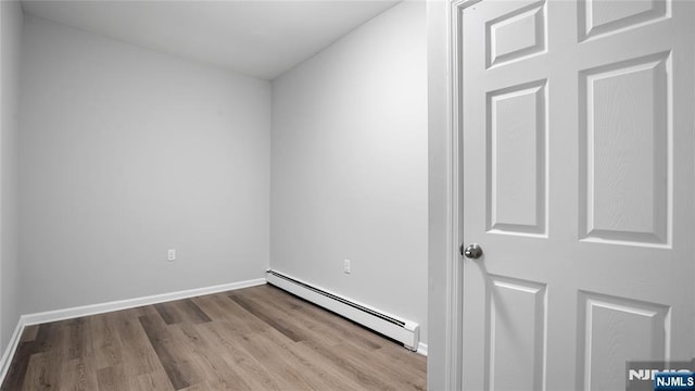 spare room with light wood-style floors, baseboards, and a baseboard heating unit