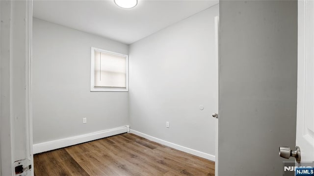 spare room featuring baseboard heating, baseboards, and wood finished floors