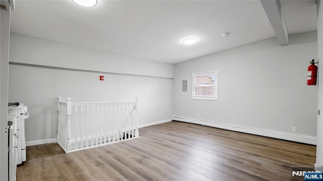 spare room featuring a baseboard radiator, beam ceiling, baseboards, and wood finished floors