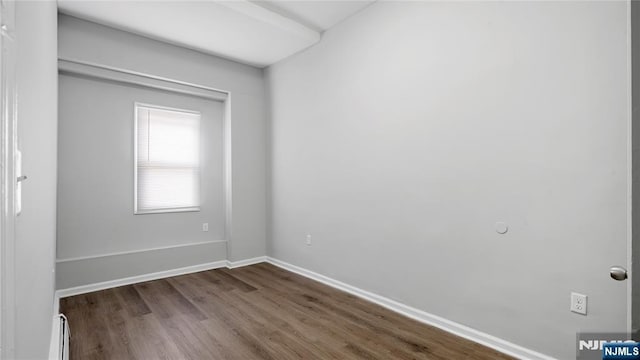 spare room with baseboards, baseboard heating, and dark wood-type flooring