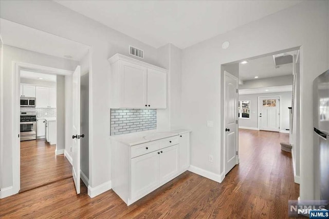 corridor with dark wood-style floors, recessed lighting, visible vents, and baseboards