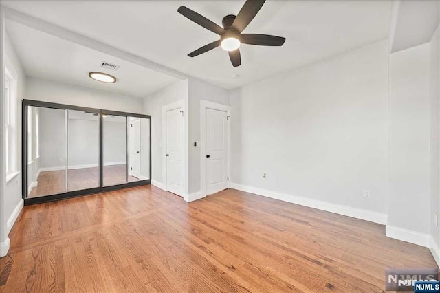 unfurnished bedroom featuring light wood-type flooring, baseboards, visible vents, and two closets