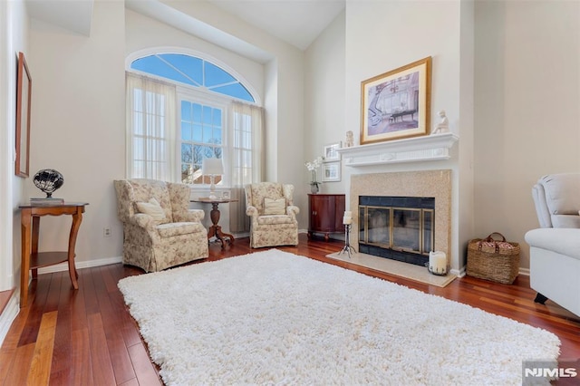 sitting room featuring dark wood-style floors, a glass covered fireplace, and baseboards