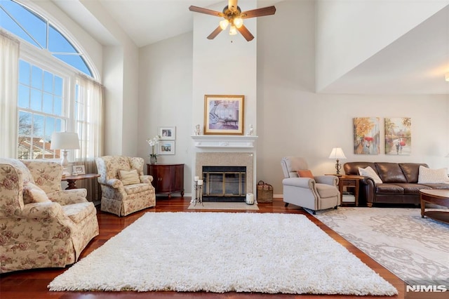 living room featuring high vaulted ceiling, dark wood finished floors, a fireplace with flush hearth, and ceiling fan