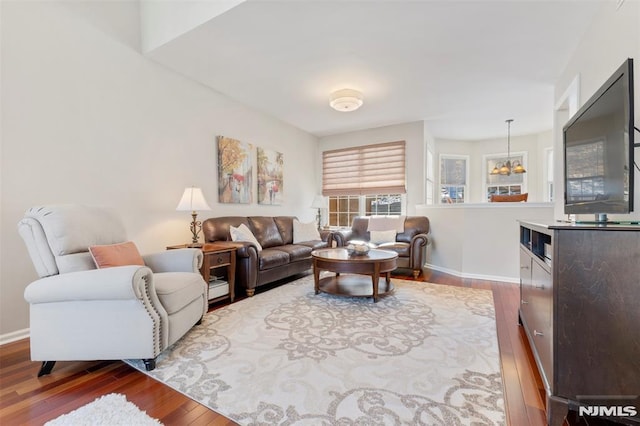 living room featuring a notable chandelier, wood finished floors, and baseboards