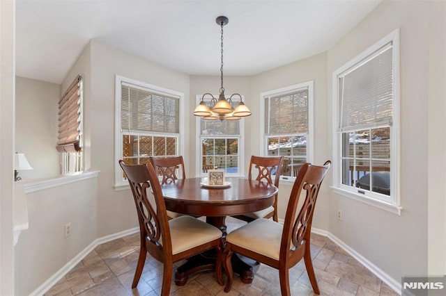 dining area with stone tile flooring, a notable chandelier, and baseboards