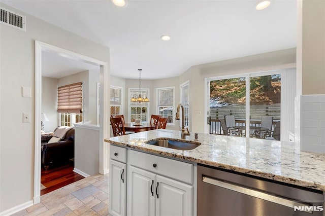 kitchen with a sink, visible vents, white cabinets, stainless steel dishwasher, and pendant lighting