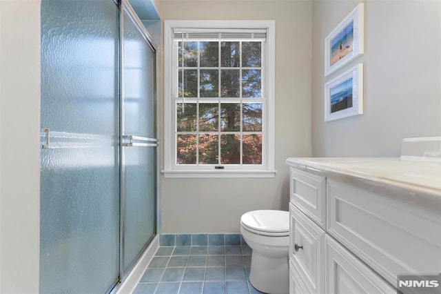 bathroom featuring toilet, a stall shower, vanity, baseboards, and tile patterned floors