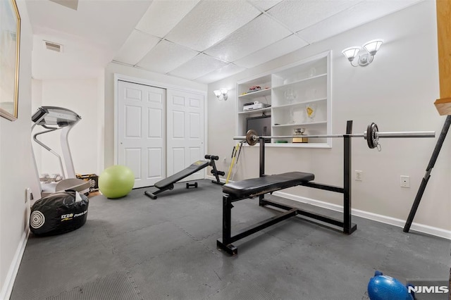 exercise area with baseboards, visible vents, and a drop ceiling