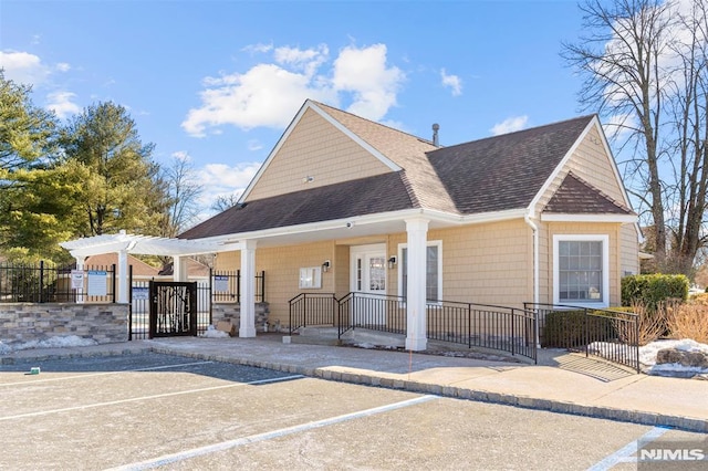 view of front of home featuring fence private yard, a gate, a pergola, and roof with shingles