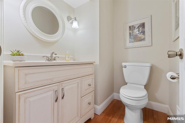 bathroom featuring baseboards, vanity, toilet, and wood finished floors