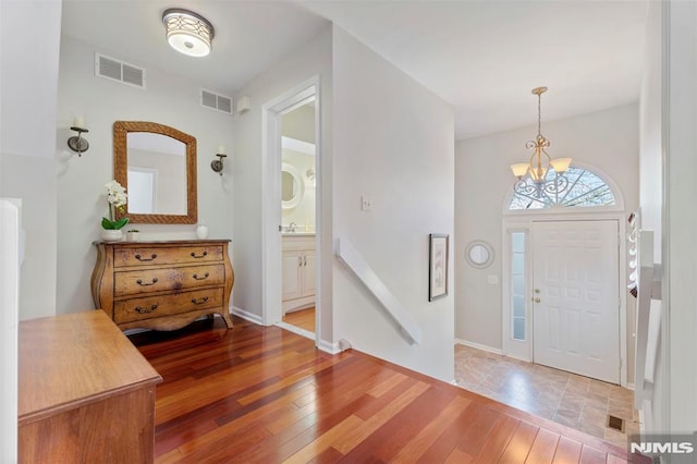 entryway featuring wood finished floors, visible vents, and a notable chandelier