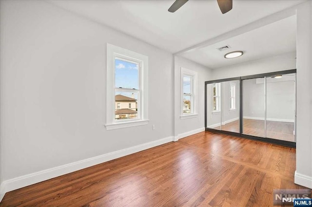 unfurnished bedroom featuring visible vents, ceiling fan, baseboards, and wood finished floors