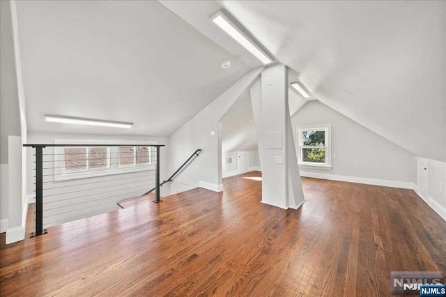 additional living space with lofted ceiling, dark wood-type flooring, and baseboards