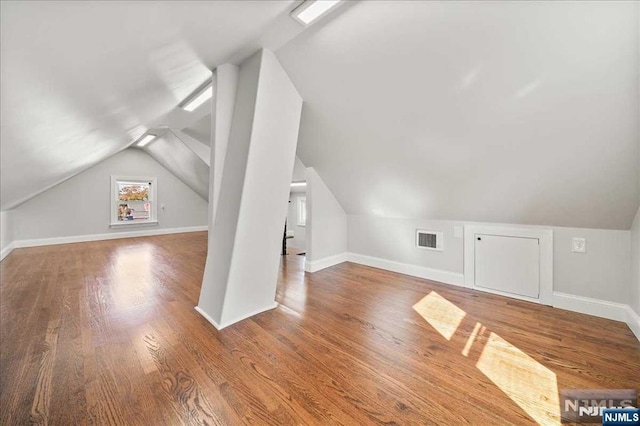 additional living space featuring baseboards, visible vents, vaulted ceiling, and wood finished floors