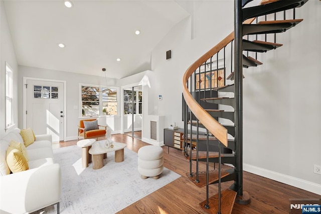 living area featuring baseboards, wood finished floors, stairs, high vaulted ceiling, and recessed lighting