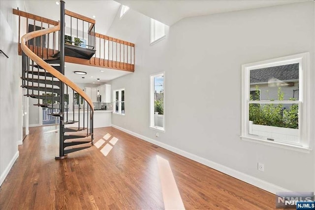 entryway with stairs, a high ceiling, wood finished floors, and baseboards