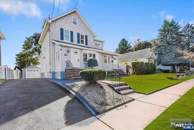 view of front of home with driveway, a detached garage, a front lawn, and an outdoor structure