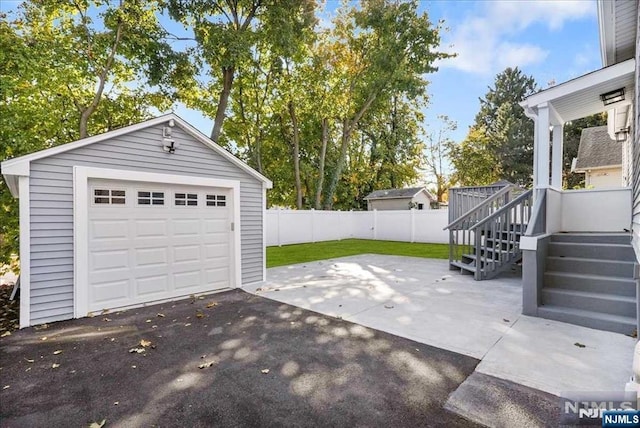 detached garage featuring aphalt driveway and fence