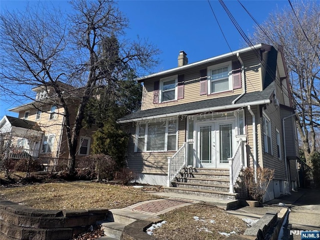 view of front of home with entry steps, roof with shingles, french doors, and a chimney