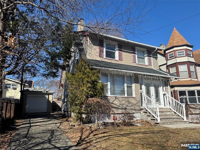 victorian house featuring a garage, driveway, an outdoor structure, and a chimney