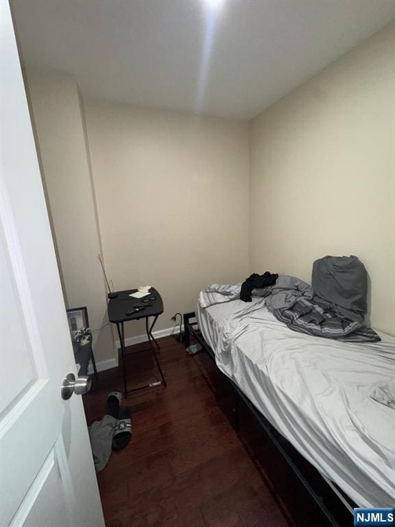 bedroom with dark wood-type flooring and baseboards