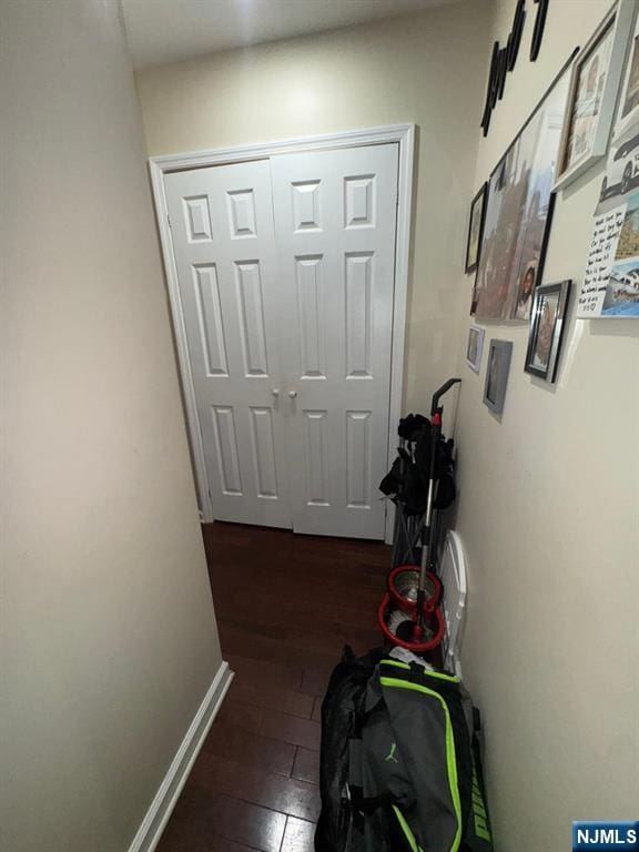 hall with dark wood-type flooring and baseboards