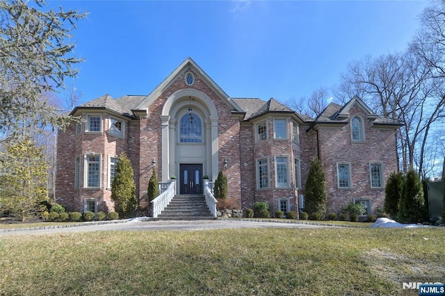 view of front of property featuring french doors, brick siding, and a front lawn