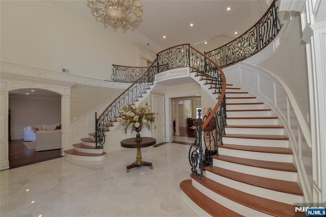 foyer entrance with ornate columns, a high ceiling, arched walkways, and a decorative wall