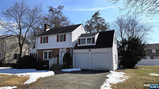 view of front of property with a garage, brick siding, fence, driveway, and a chimney