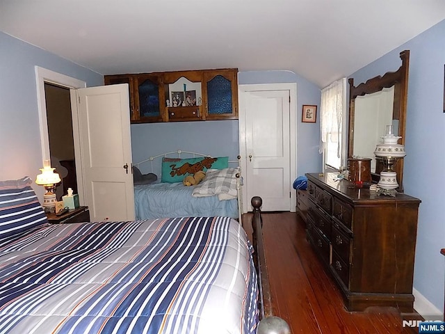 bedroom with vaulted ceiling and dark wood-type flooring