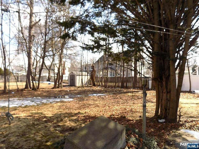 view of yard featuring fence, a storage unit, and an outbuilding