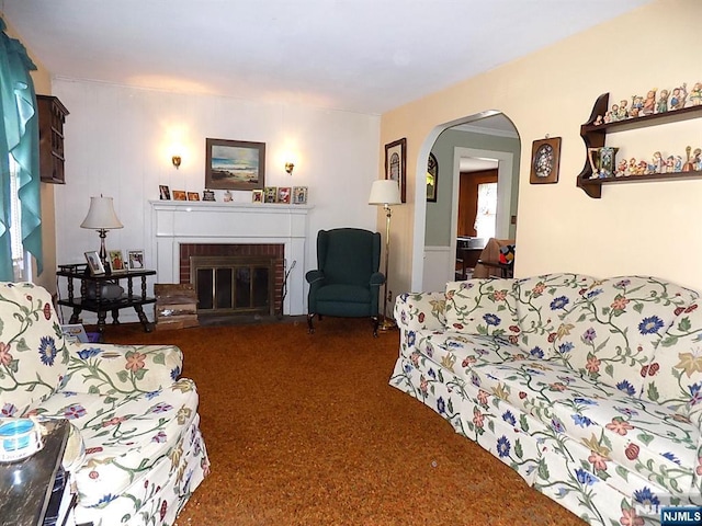 living room featuring a fireplace, arched walkways, and dark colored carpet