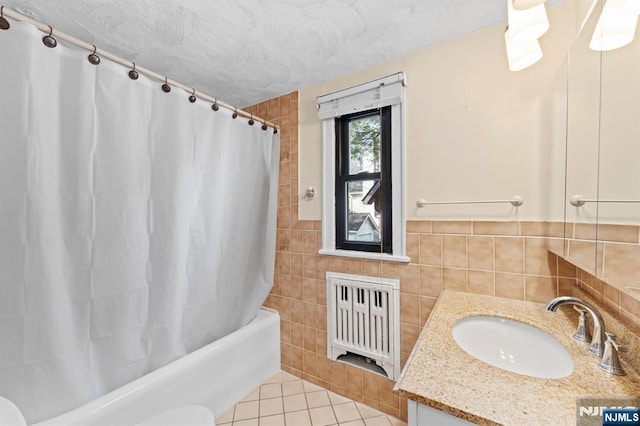 bathroom with tile walls, shower / tub combo, vanity, a textured ceiling, and tile patterned floors