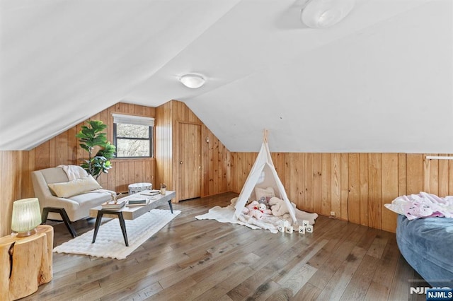 additional living space with wood walls, wood-type flooring, and vaulted ceiling