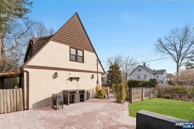 view of home's exterior featuring a lawn, fence, a patio, and stucco siding