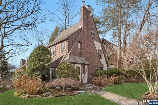 view of home's exterior featuring roof with shingles, a lawn, and a chimney